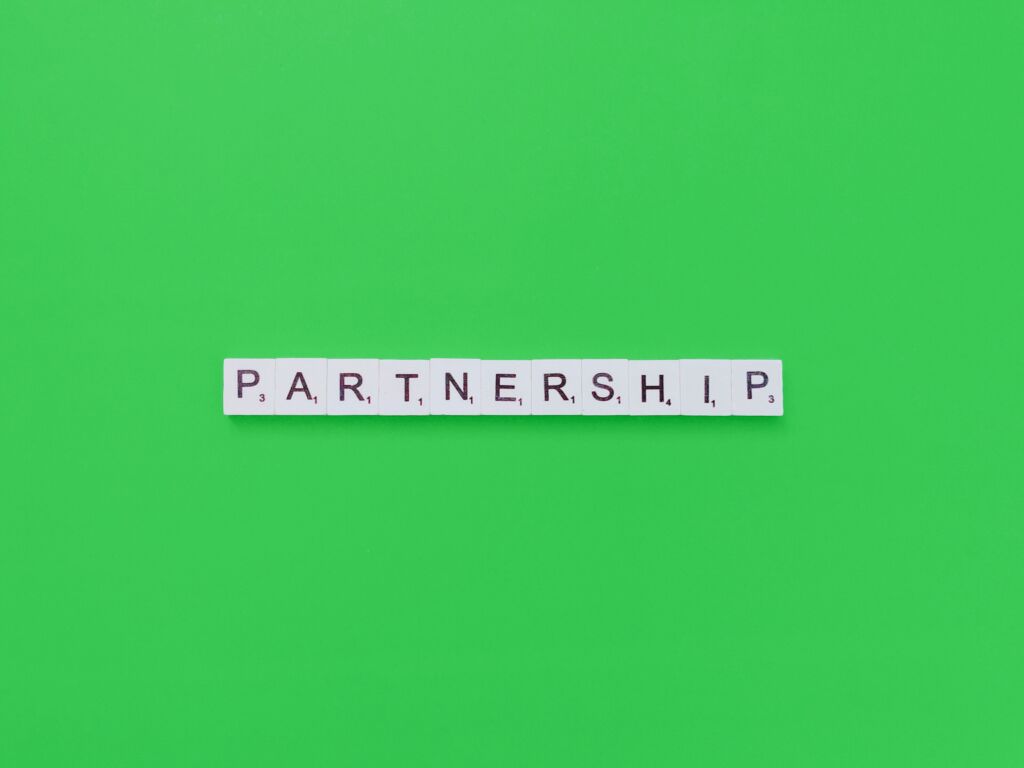 the word 'partnership' spelled out on white tiles with black letters on a green background